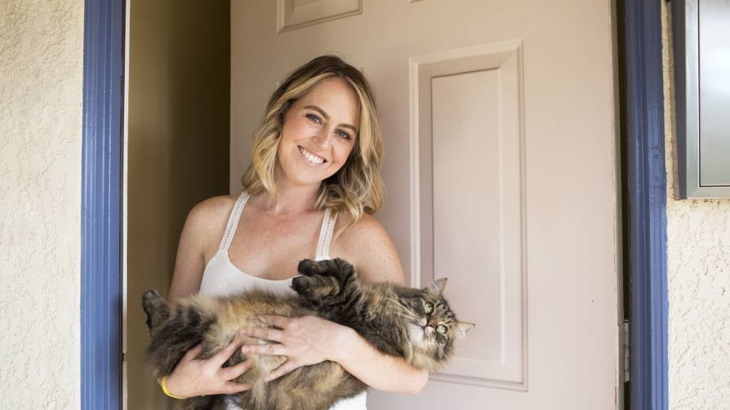 Young woman stands at door of rental with her cat