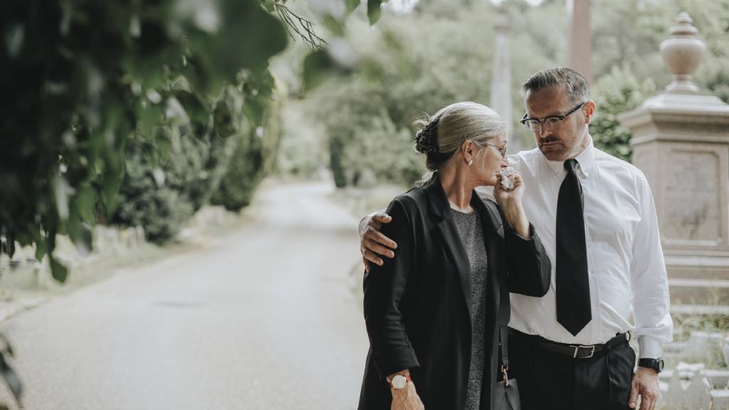 man comforting woman at funeral 