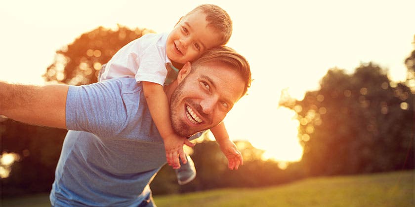 father playing with child outdoors 