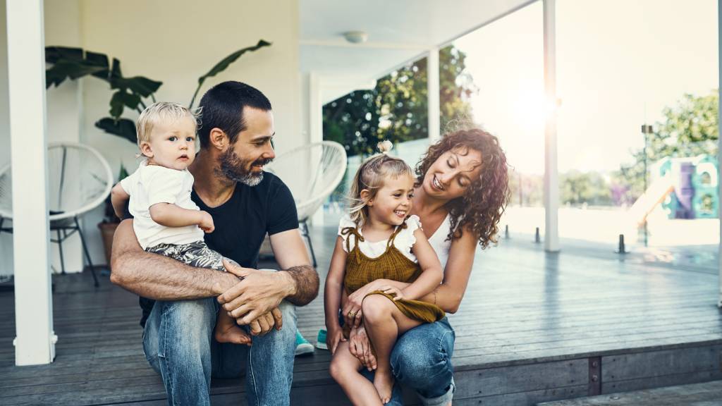 Modern mother and father with two children at home on veranda