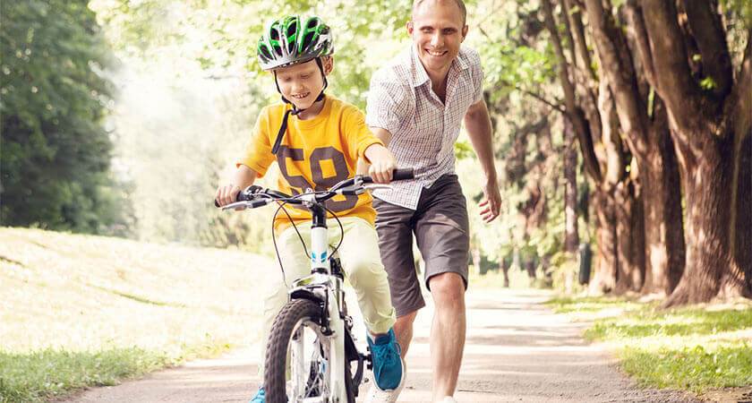 father teaching child how to ride bike