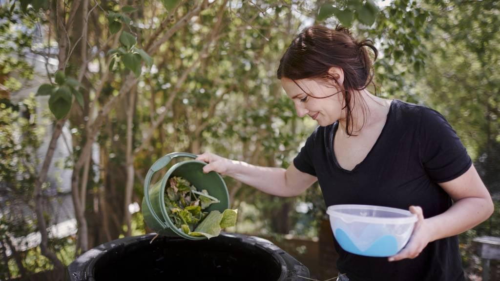Woman mixes green matter and water into compost