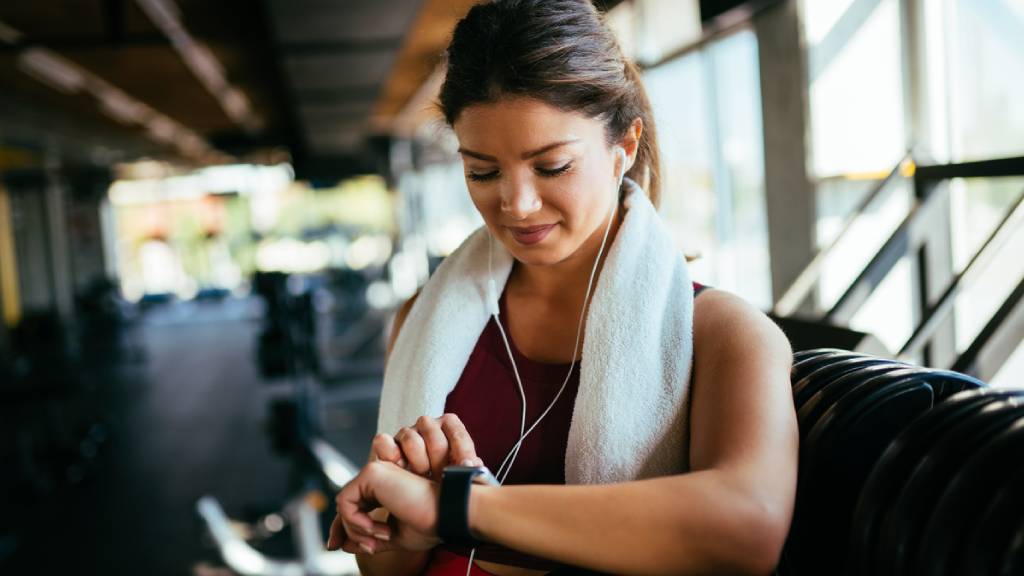 Woman in active wear checking her interval training time on smartwatch 