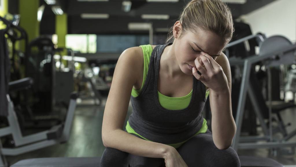 Woman in a gym with a headache after workout