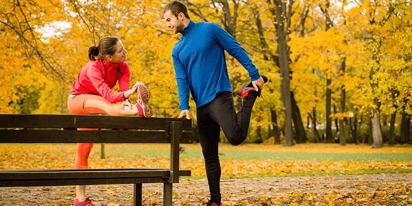man and woman running and stretching outdoors