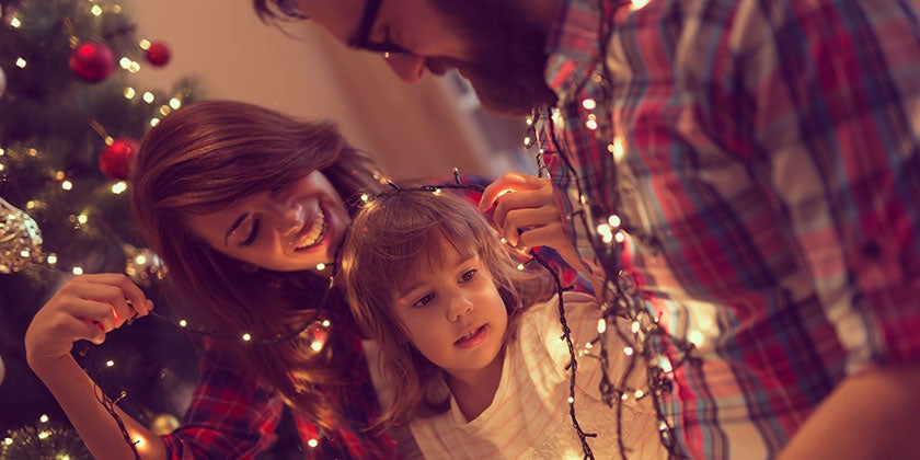parents putting up christmas lights with child