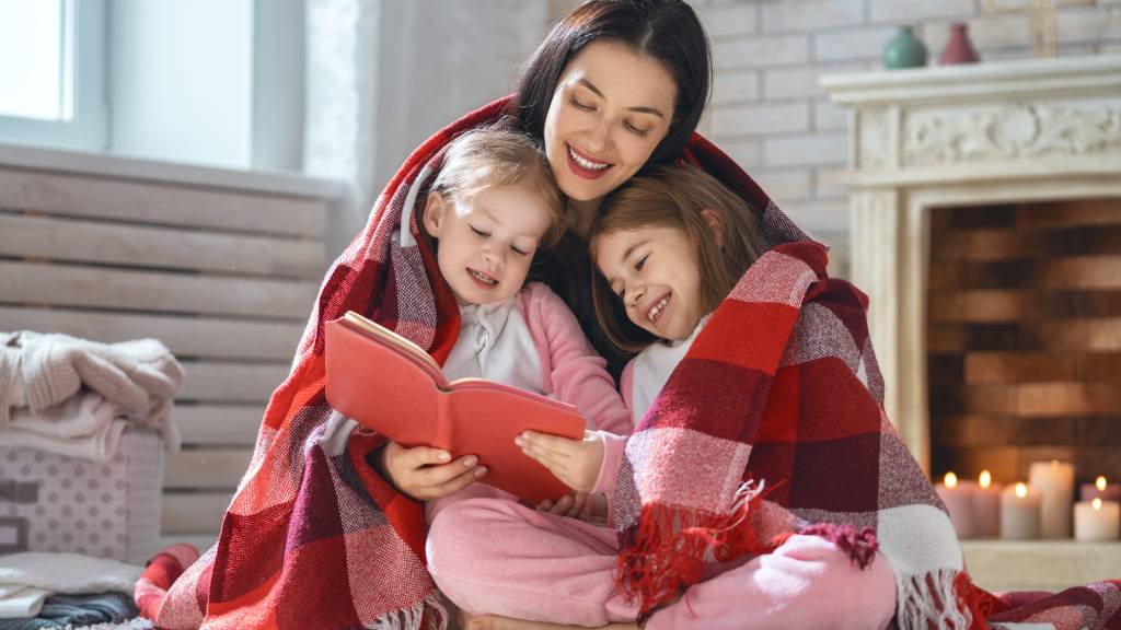 Woman keeping warm with children under blanket 