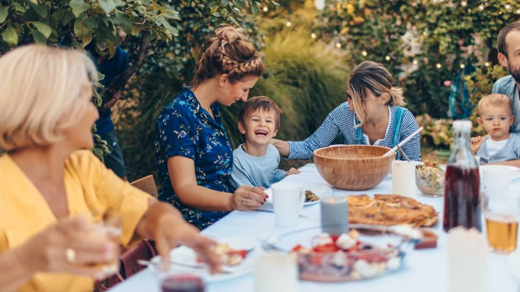 Family at outdoor table enjoying a meal together. 