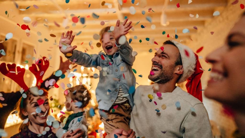 Group of family with children in their arms wearing a Santa hat celebrating with confetti