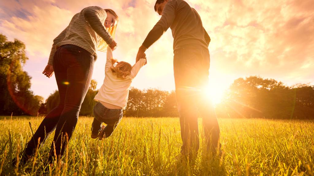 parents hold baby's hands happy family in park evening