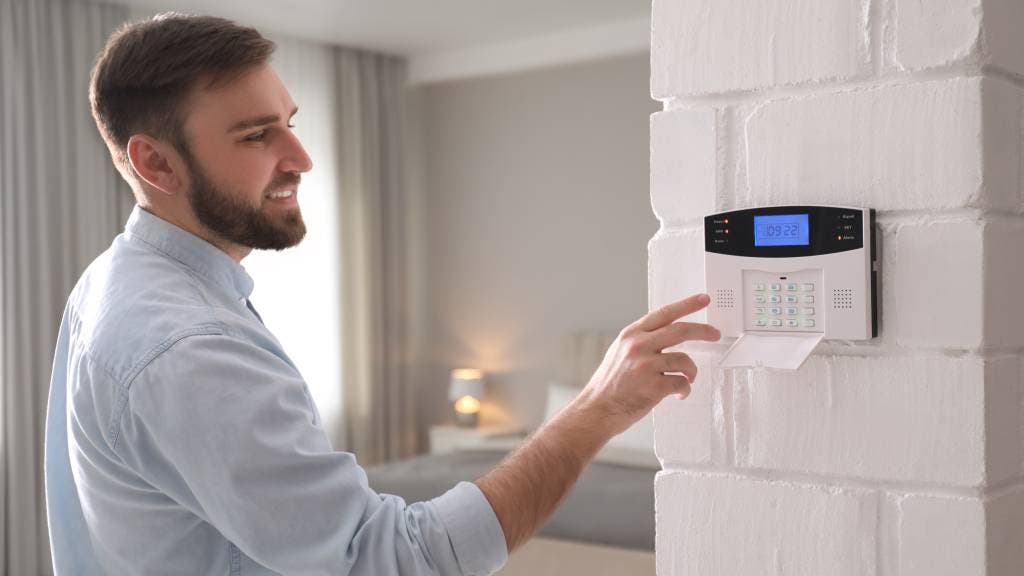 Man entering code on security alarm system in bedroom