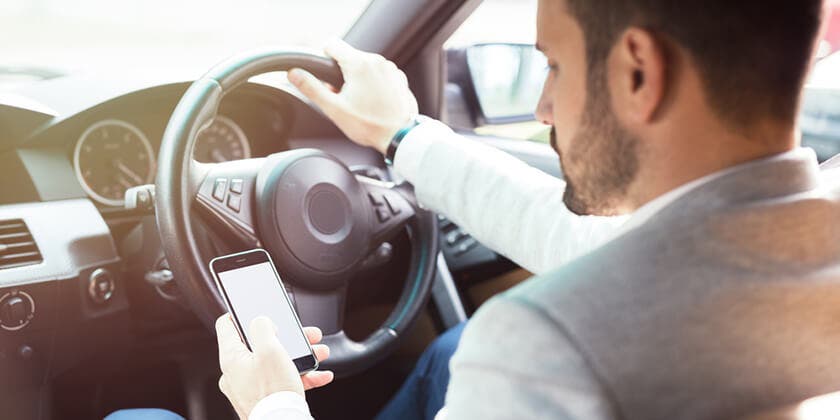 driver illegally using phone in car, illustrating penalty offences 