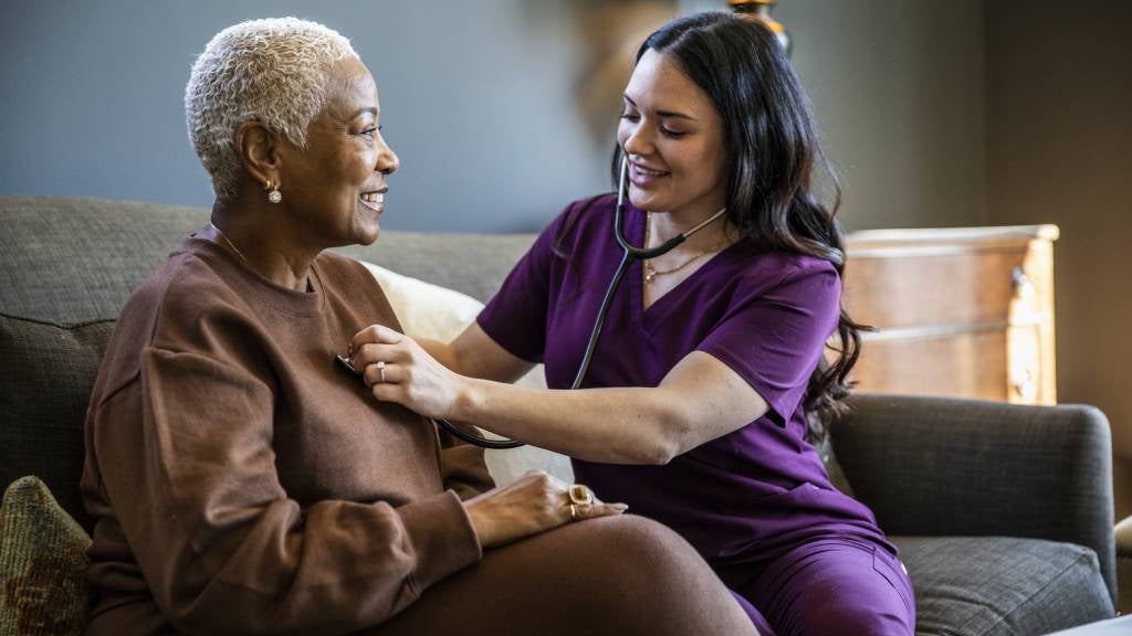 A nurse checks a woman’s heartbeat with a stethoscope
