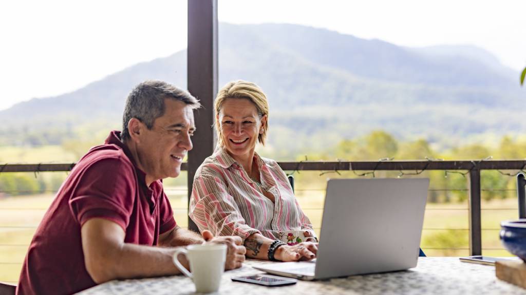 mid aged couple talking about life insurance using laptop 