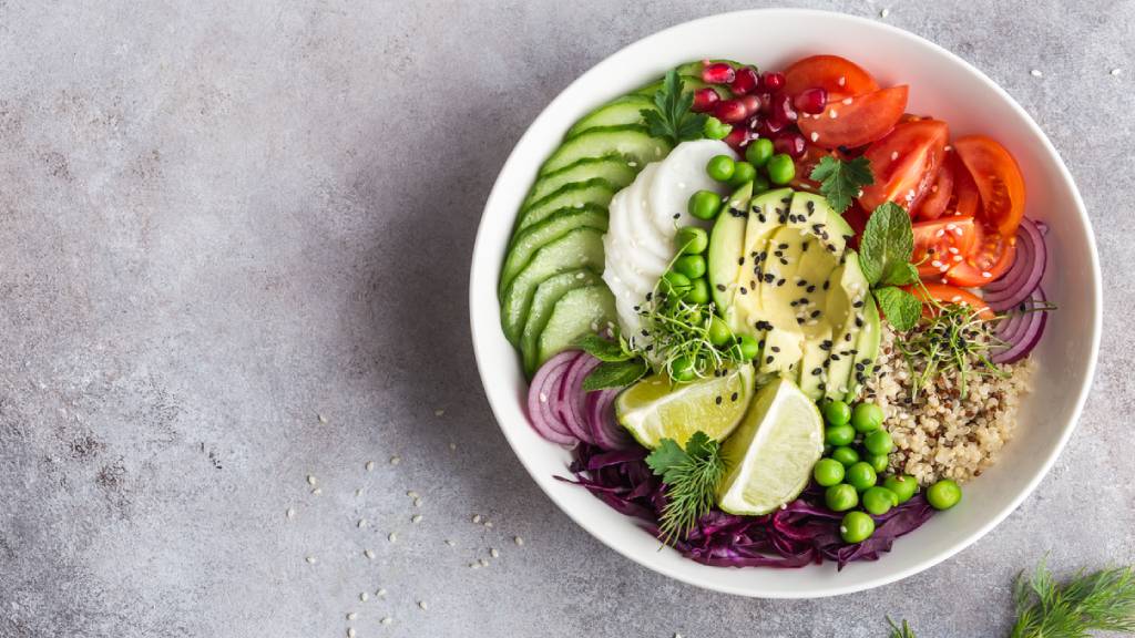 Bowl of vegan food including avocado, brown rice and tomatoes 