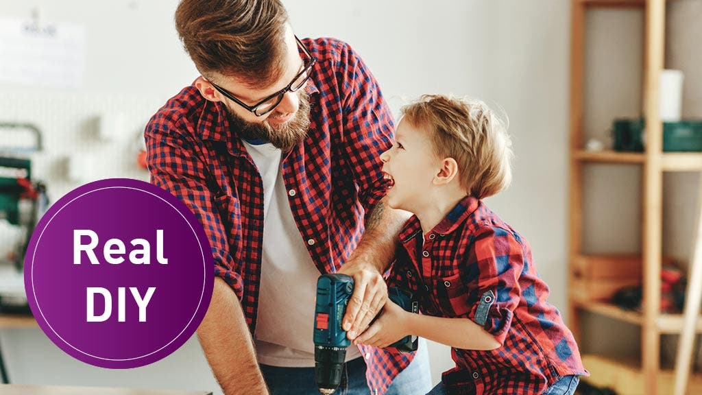 Father and son work on tools together in a shed.