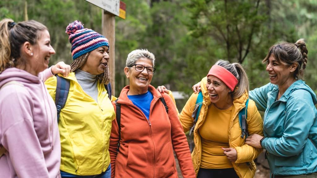 A group of women of various ages in bright winter clothes; smiling and happy. 