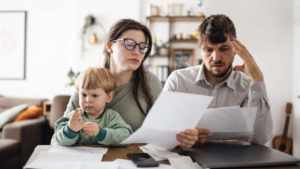 A young family sifts through insurance documents at the dining table. 