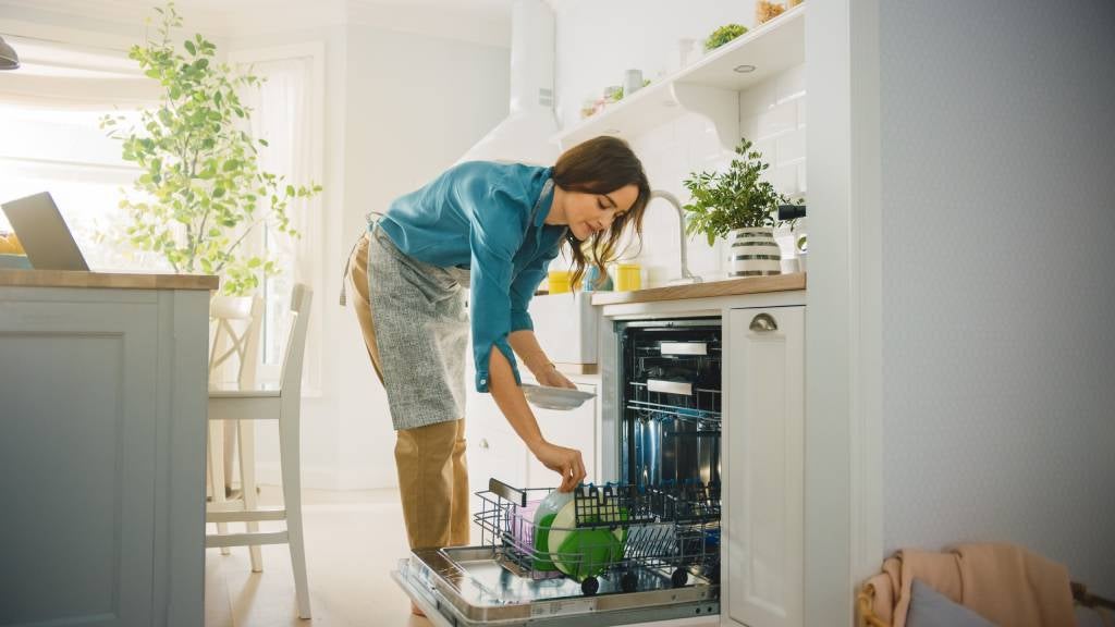 Woman in blue shirt unloads a dishwasher