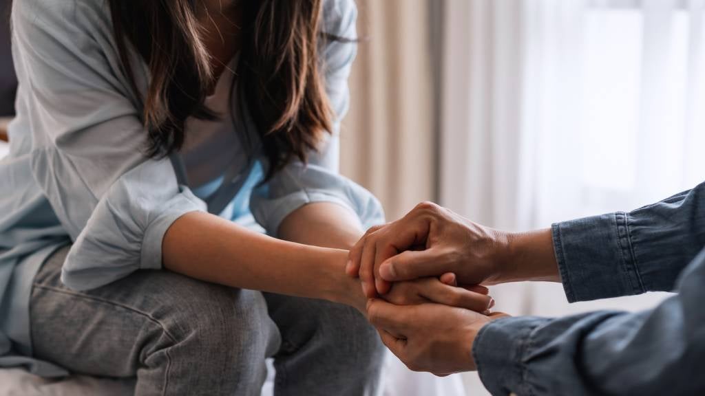 Man and woman hold hands after dealing with sudden loss of a loved one. 