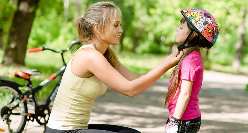 mother putting helmet on child