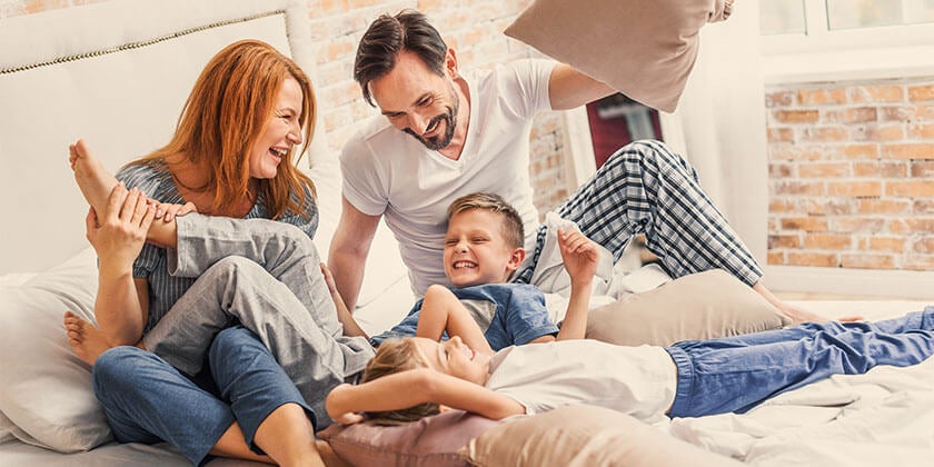 young family playing on bed 