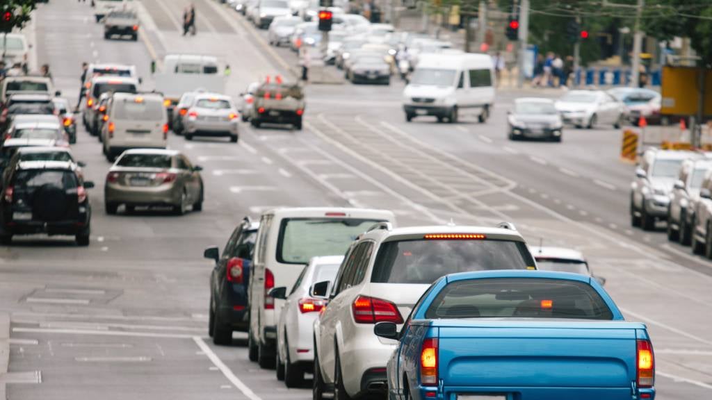 Busy city road with cars stopped at traffic lights and other cars going at a green signal