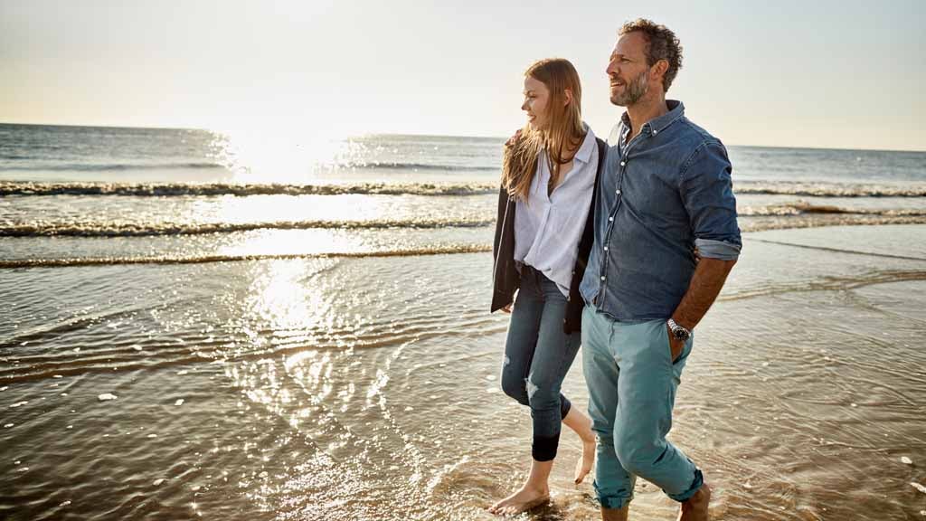 couple in 40s walking along beach
