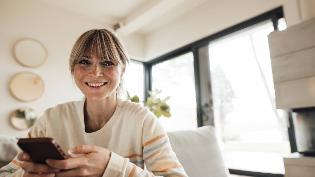 Woman in her forties uses a smartphone to plan her finances