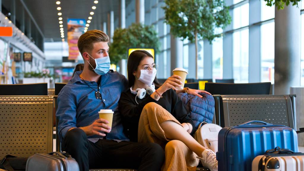 Young couple wearing N95 face masks waiting in airport area