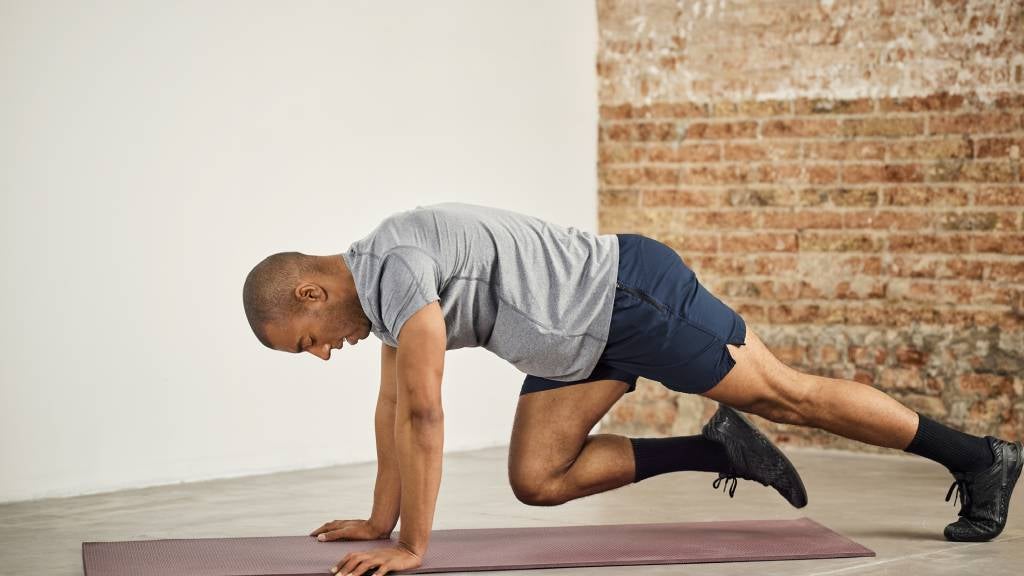 Man exercises on floor mat with leg lifts