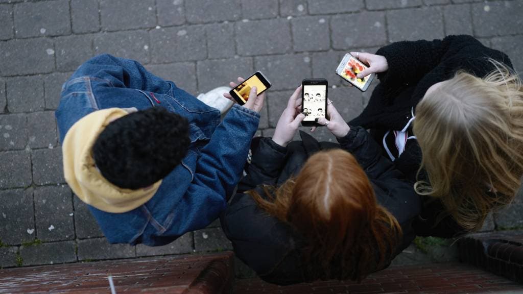Three teenagers on smartphones, pictured from above