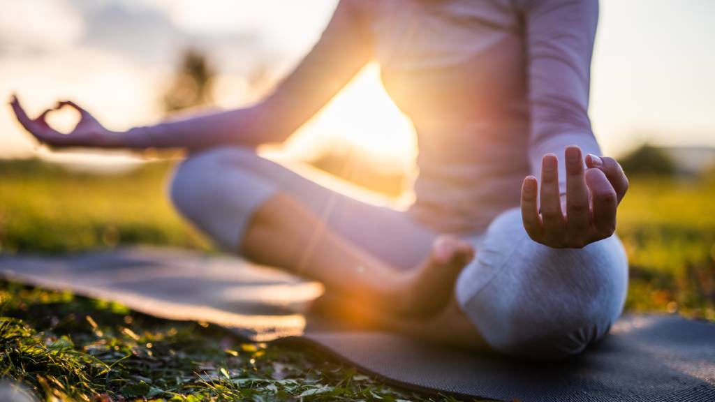 Woman in grey active wear meditating in sukhasana yoga pose