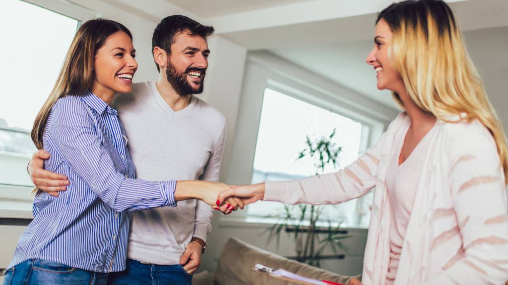 Couple shaking hands with a realtor, buying a home 