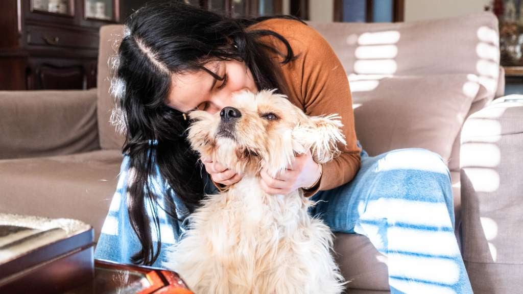 Woman hugging her dog in her living room