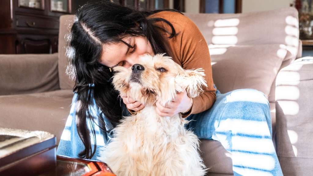 Woman hugging her dog in her living room