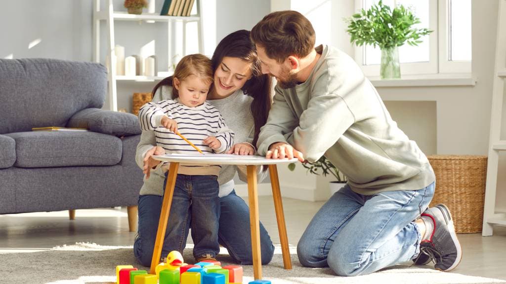 Mother and father play with their toddler aged son on the floor
