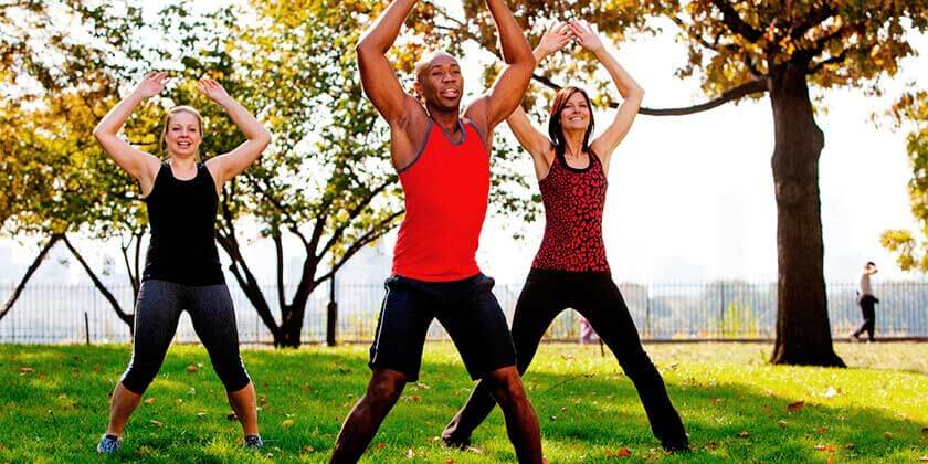 group doing jumping jacks in park