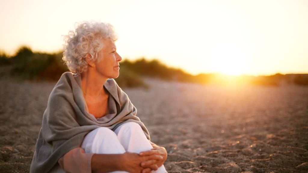 Mature woman on beach looking into horizon 
