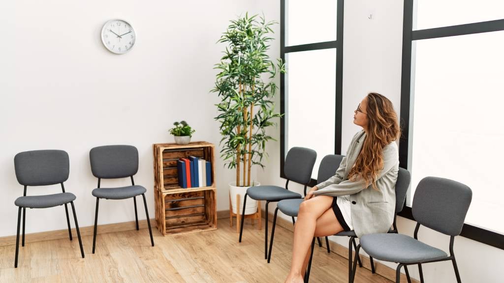 A woman looks at the clock while sitting in a waiting room