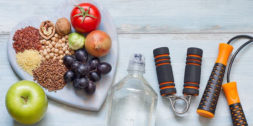 Healthy fruit and grains on heart shaped cutting board with water bottle, apple and fitness equipment 