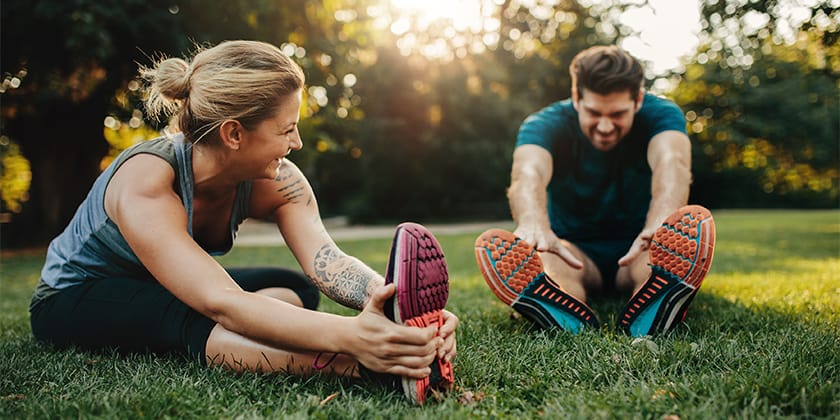 man and woman stretching at park in the morning