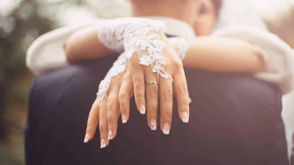 Bride and groom on wedding day - detail of fingers and rings