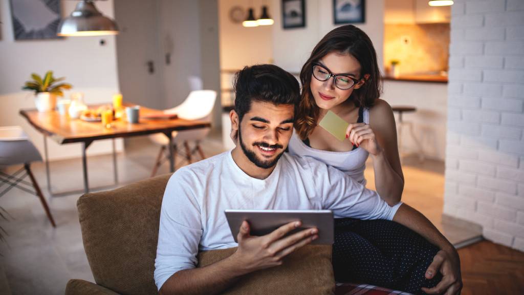 Couple smiling and looking at laptop together.