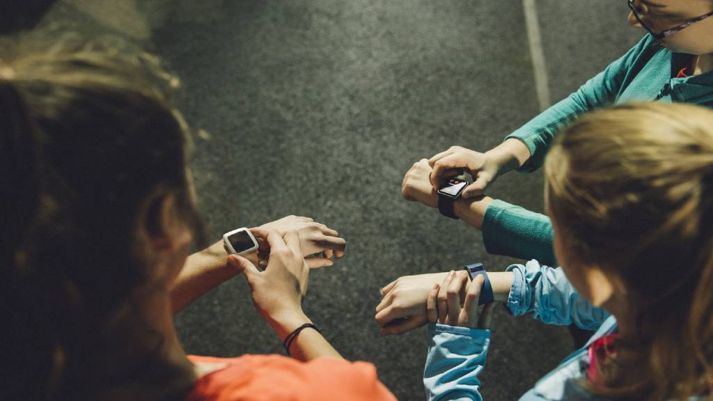 Group of three runners looking at their wearable fitness technology devices