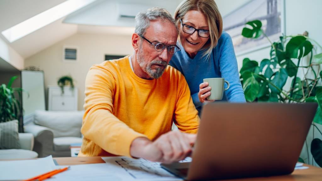 Couple in their sixties plans finances on a laptop