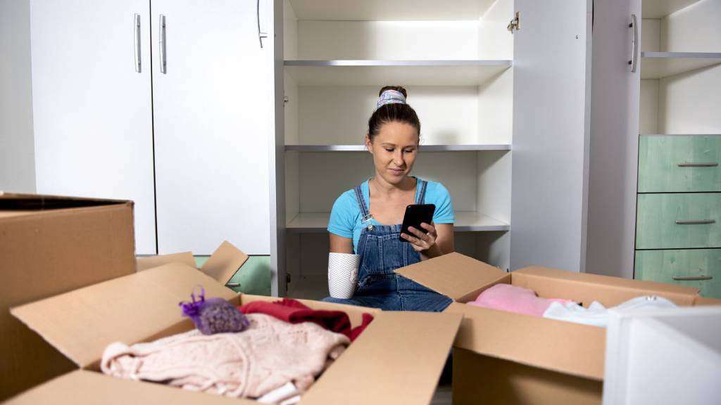 single woman using phone while moving into new home