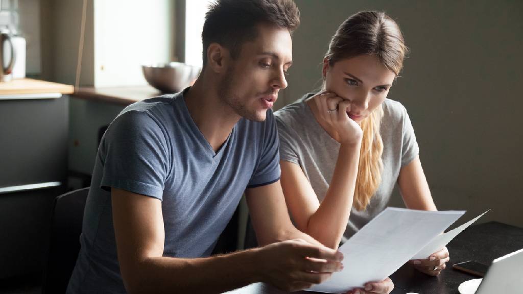 young couple discussing life insurance and looking at paperwork 