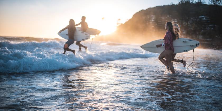 surfers entering water on australian beach