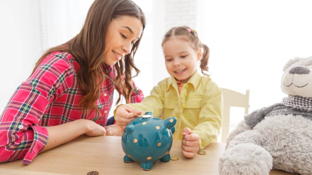 mother teaching daughter about money piggy bank 